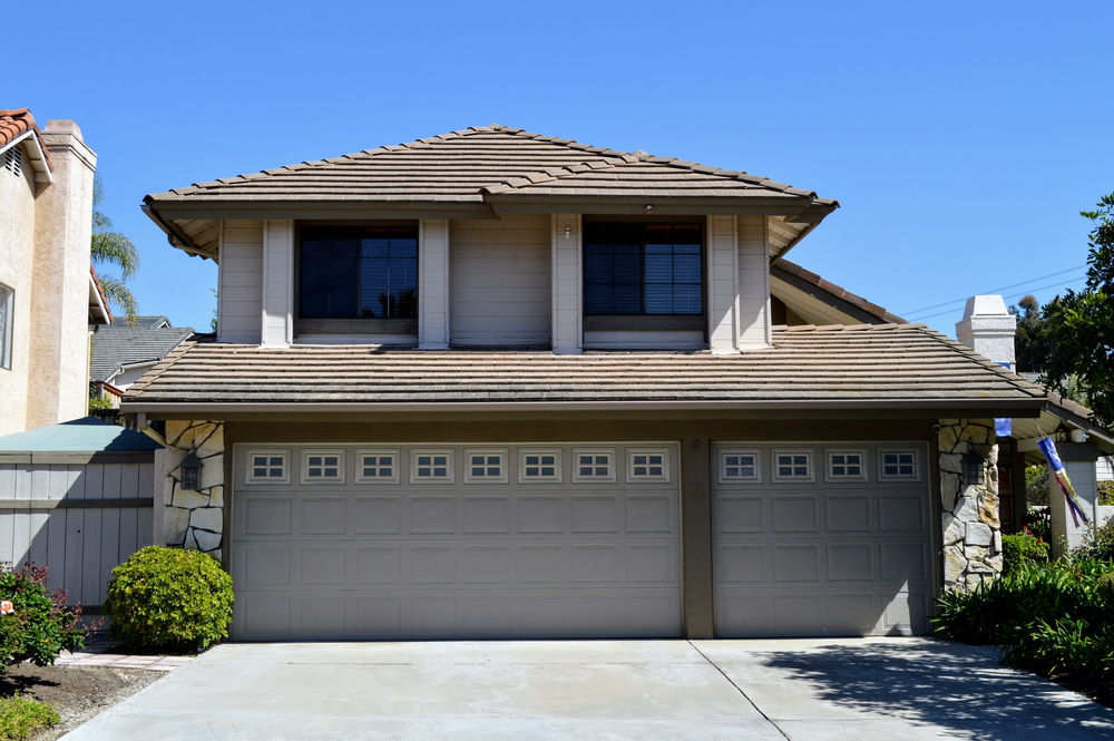 Front exterior view of a two-story suburban house featuring a large three-car garage and landscaped yard – JP Buys SD